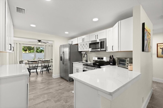 129 Rogers Pl, Port Orange, FL 32127 - kitchen featuring appliances with stainless steel finishes, a ceiling fan, white cabinets, recessed lighting, and a peninsula