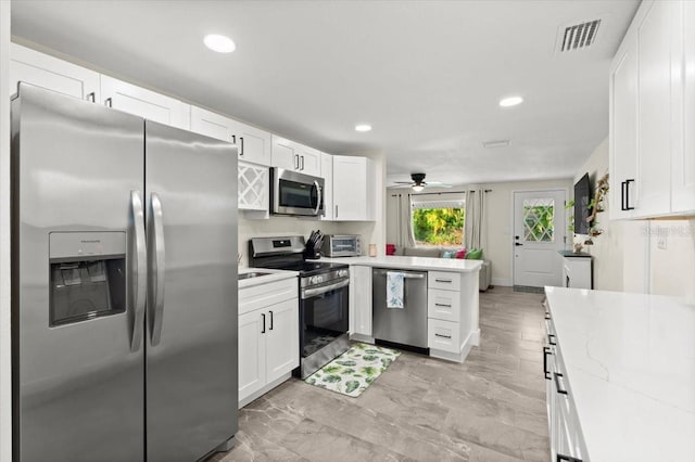 129 Rogers Pl, Port Orange, FL 32127 - kitchen with appliances with stainless steel finishes, a peninsula, white cabinetry, and recessed lighting