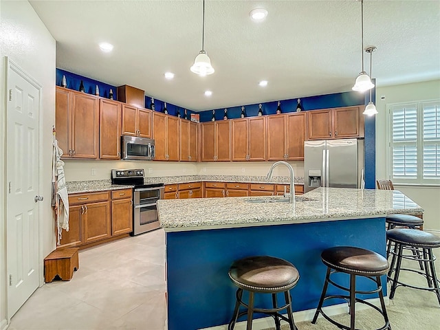 3361 Pegaso Ave, New Smyrna Beach, FL 32168 - kitchen with appliances with stainless steel finishes, brown cabinets, a kitchen bar, decorative light fixtures, and recessed lighting