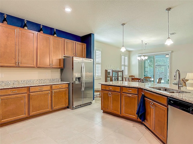 3361 Pegaso Ave, New Smyrna Beach, FL 32168 - kitchen featuring appliances with stainless steel finishes, brown cabinetry, a chandelier, light stone counters, and hanging light fixtures