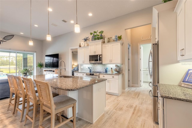 2931 Bella Flore Ter, New Smyrna Beach, FL 32168 - kitchen with appliances with stainless steel finishes, white cabinetry, light stone counters, tasteful backsplash, and a kitchen bar