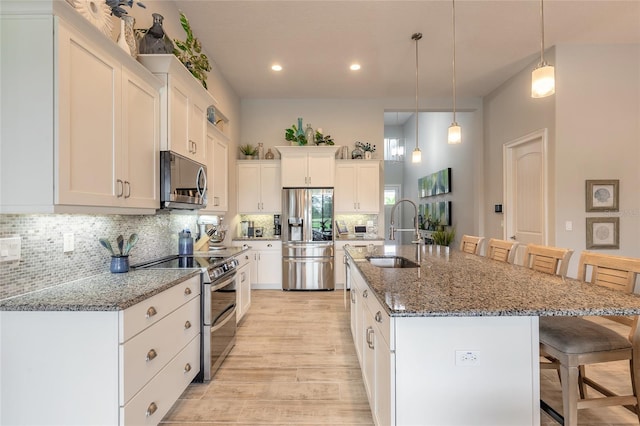 2931 Bella Flore Ter, New Smyrna Beach, FL 32168 - kitchen with stainless steel appliances, a kitchen bar, light wood-type flooring, backsplash, and white cabinetry