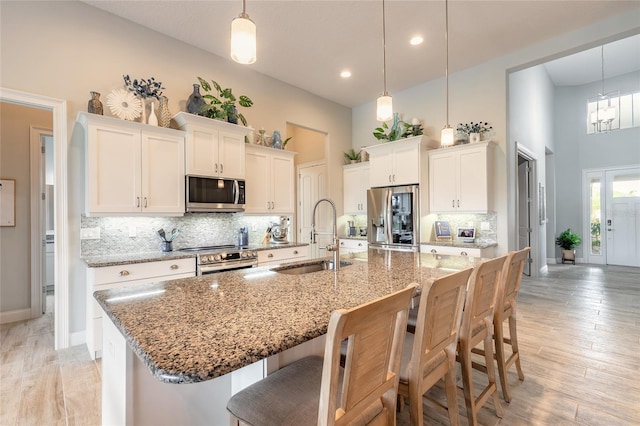 2931 Bella Flore Ter, New Smyrna Beach, FL 32168 - kitchen with appliances with stainless steel finishes, a high ceiling, a breakfast bar, white cabinets, and decorative backsplash