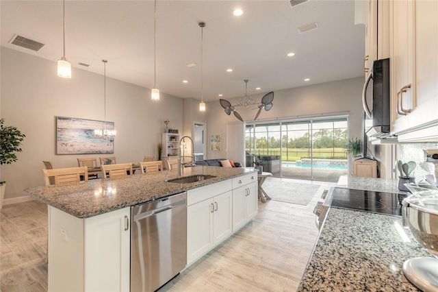 2931 Bella Flore Ter, New Smyrna Beach, FL 32168 - kitchen featuring appliances with stainless steel finishes, a chandelier, a kitchen island with sink, stone counters, and recessed lighting