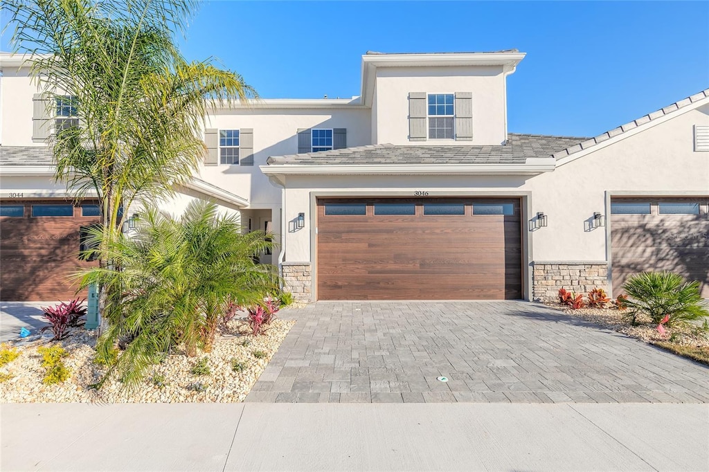 3044 Isles Way, New Smyrna Beach, FL 32168 - view of front of property with stone siding, decorative driveway, stucco siding, and a garage