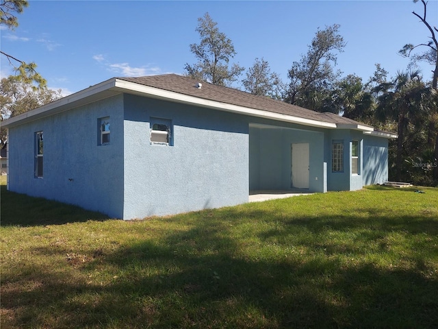 back of house with a yard and stucco siding