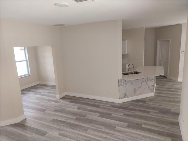 unfurnished room featuring baseboards, a sink, and wood finished floors