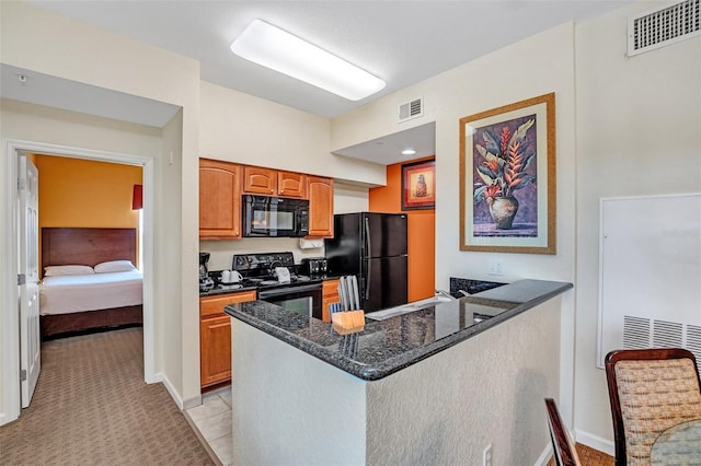 kitchen with sink, black appliances, light tile patterned flooring, kitchen peninsula, and dark stone counters