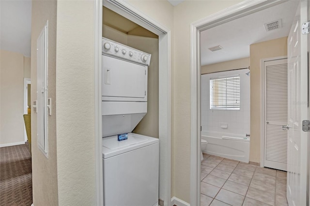 laundry room with light tile patterned floors and stacked washing maching and dryer