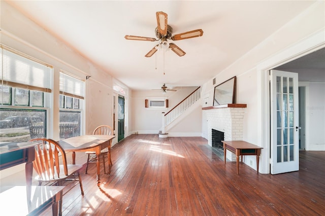 interior space with an AC wall unit, a brick fireplace, ceiling fan, and dark hardwood / wood-style flooring