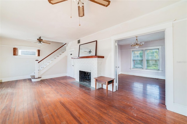 unfurnished living room with a fireplace, dark wood-type flooring, and ceiling fan with notable chandelier