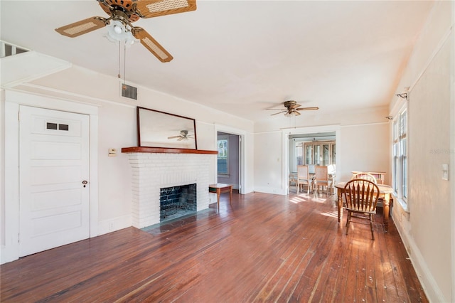 unfurnished living room with dark hardwood / wood-style floors, ceiling fan, and a fireplace