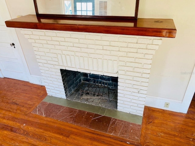 interior details featuring a brick fireplace and wood-type flooring