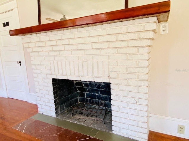 details featuring a brick fireplace, wood-type flooring, and ceiling fan