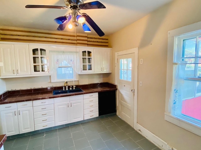 kitchen with light tile floors, ceiling fan, white cabinetry, and sink