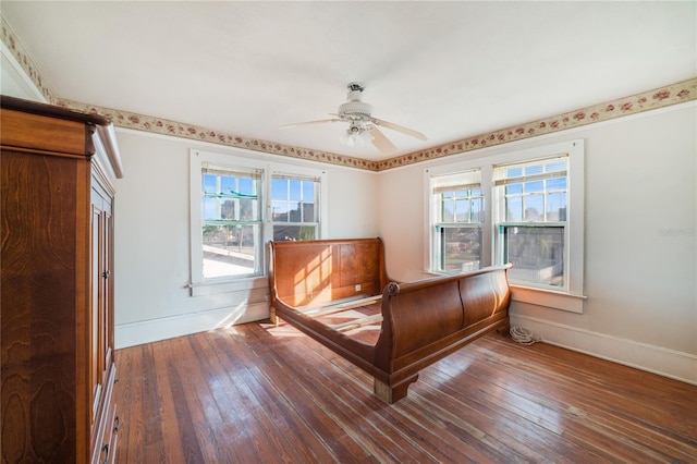 unfurnished bedroom with ceiling fan, multiple windows, and dark hardwood / wood-style floors