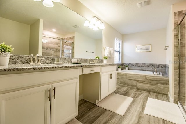 bathroom featuring a notable chandelier, double sink vanity, and independent shower and bath