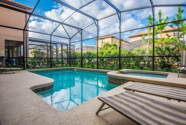 view of pool with an in ground hot tub, glass enclosure, and a patio