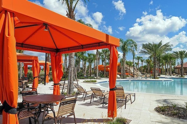 view of swimming pool featuring a water slide, a gazebo, and a patio