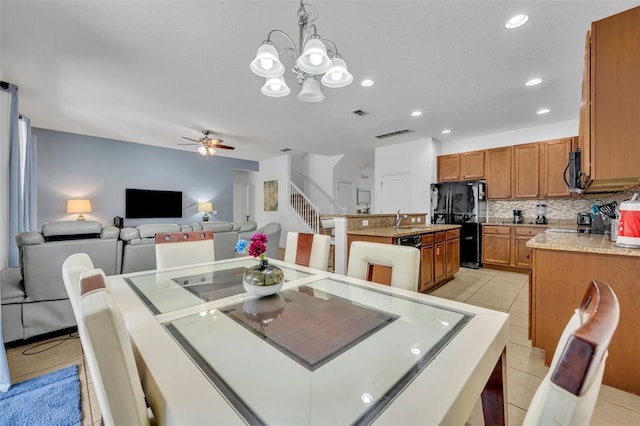 dining room with sink, light tile patterned flooring, and ceiling fan with notable chandelier