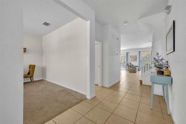 hall with a textured ceiling and light carpet