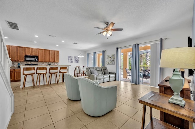 living room with ceiling fan with notable chandelier, a textured ceiling, and light tile patterned floors