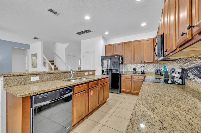 kitchen with black appliances, sink, light stone countertops, an island with sink, and light tile patterned floors