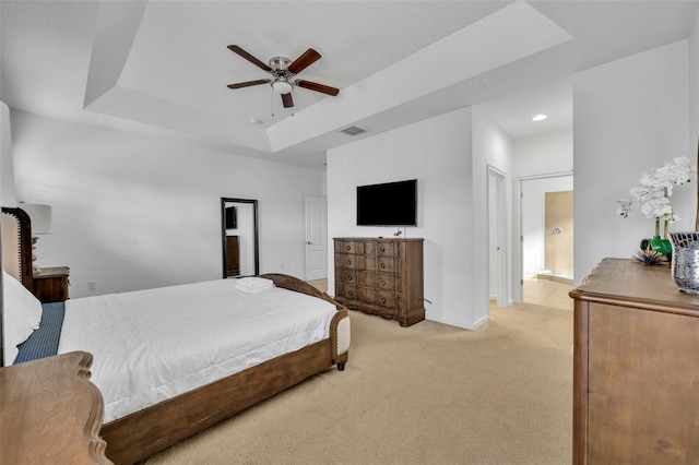 carpeted bedroom with ceiling fan, connected bathroom, and a raised ceiling