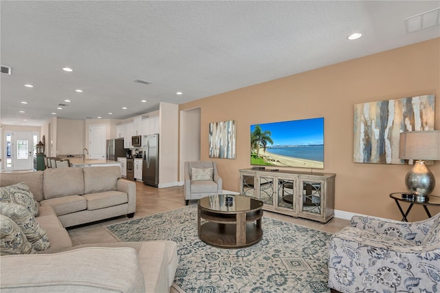 living room with light tile flooring, sink, and a textured ceiling