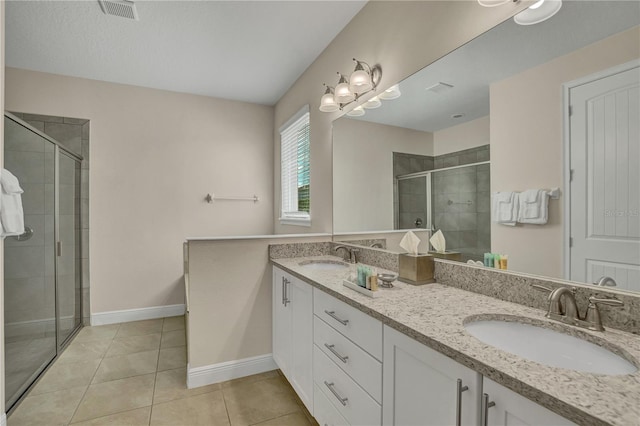 bathroom with a shower with door, double sink vanity, and tile floors