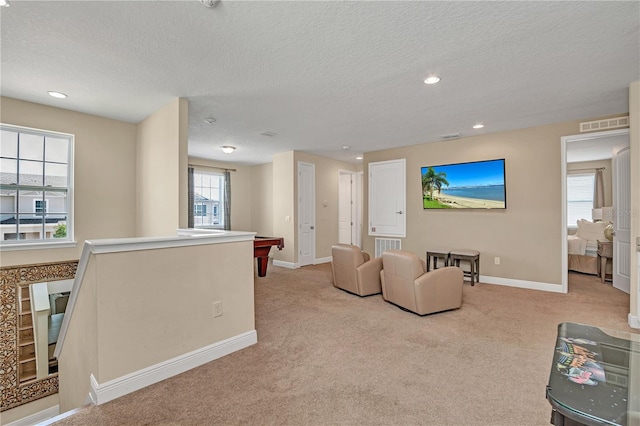 living room featuring a textured ceiling, plenty of natural light, pool table, and light carpet