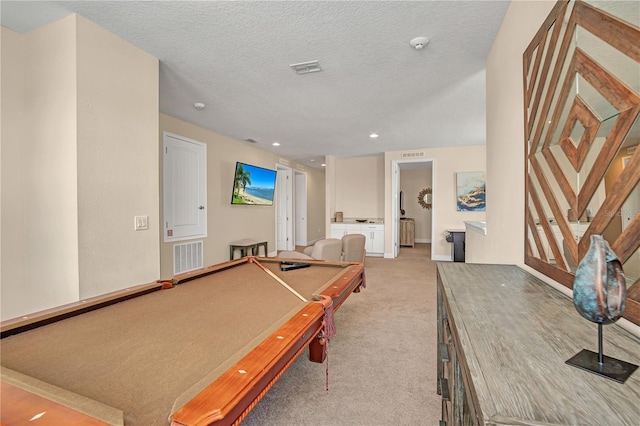 recreation room with billiards, a textured ceiling, and light colored carpet