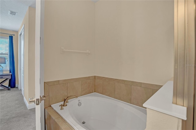 bathroom featuring tiled tub and a textured ceiling