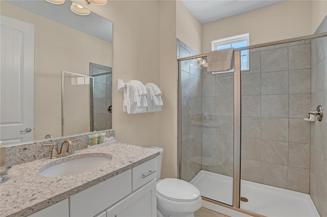 bathroom featuring toilet, large vanity, and a shower with shower door