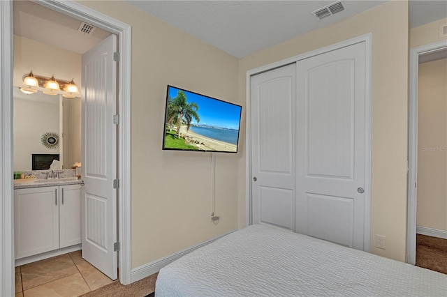 bedroom featuring a closet, sink, light tile flooring, and connected bathroom