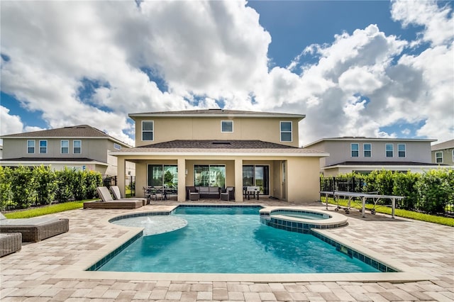 rear view of house featuring a pool with hot tub and a patio