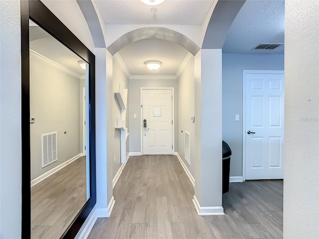 hallway with ornamental molding, hardwood / wood-style flooring, and a textured ceiling