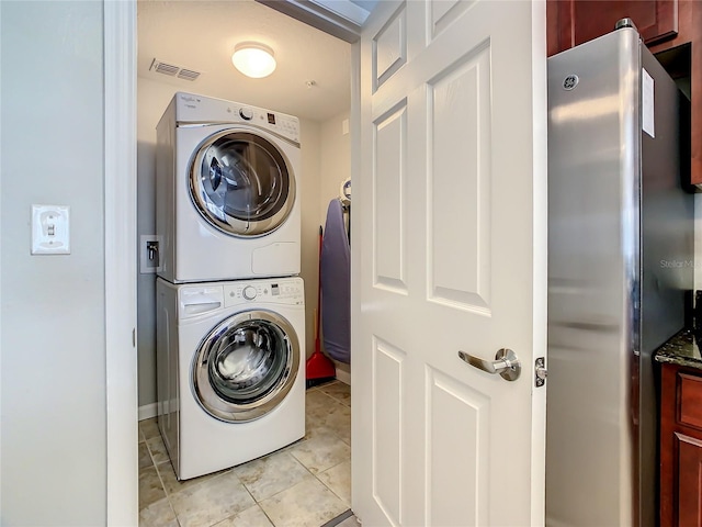 washroom with stacked washing maching and dryer, hookup for a washing machine, and light tile floors