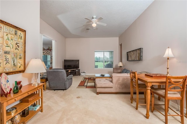 living room with light carpet, a textured ceiling, and ceiling fan