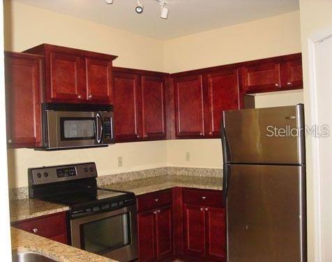 kitchen featuring appliances with stainless steel finishes, rail lighting, and light stone countertops