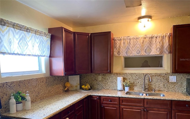 kitchen featuring light stone countertops, tasteful backsplash, and sink