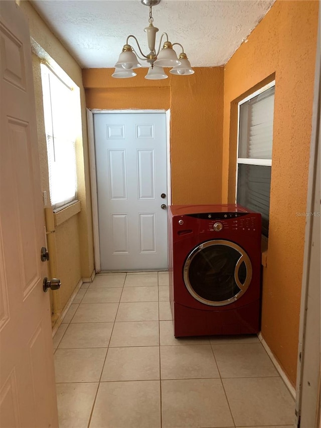 laundry area featuring washer / clothes dryer, a textured ceiling, light tile patterned floors, and an inviting chandelier