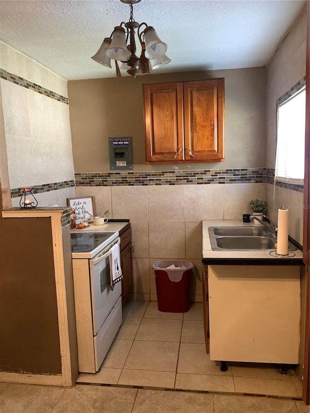 kitchen with a chandelier, tile walls, white range with electric cooktop, and light tile patterned floors