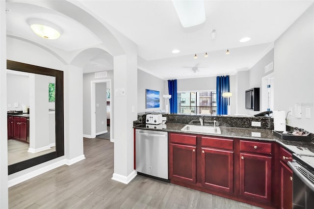 kitchen featuring dishwasher, range, sink, and dark stone counters