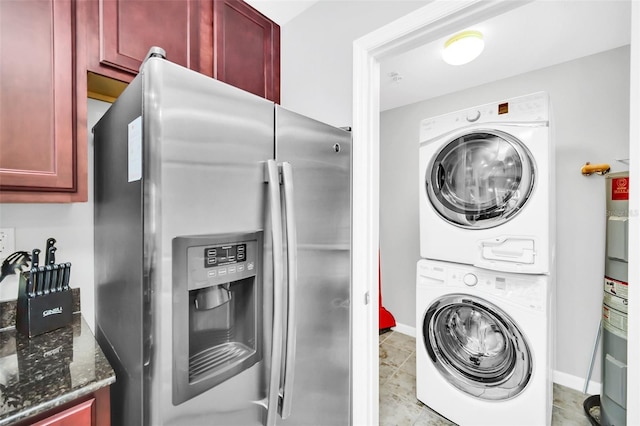 clothes washing area featuring light tile patterned floors, stacked washer and clothes dryer, and water heater