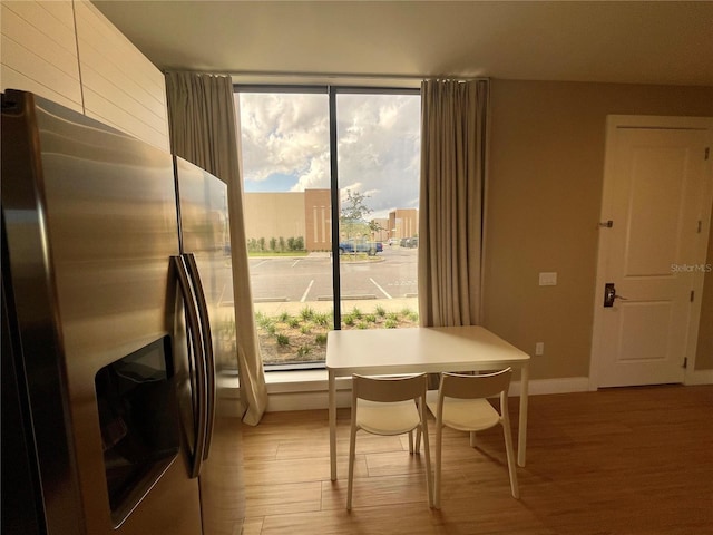 dining space featuring a healthy amount of sunlight, light wood-type flooring, and baseboards