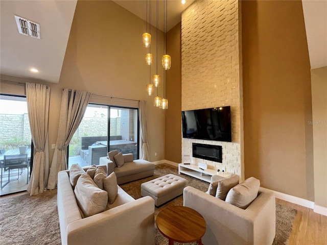 living room featuring high vaulted ceiling, a fireplace, visible vents, and baseboards