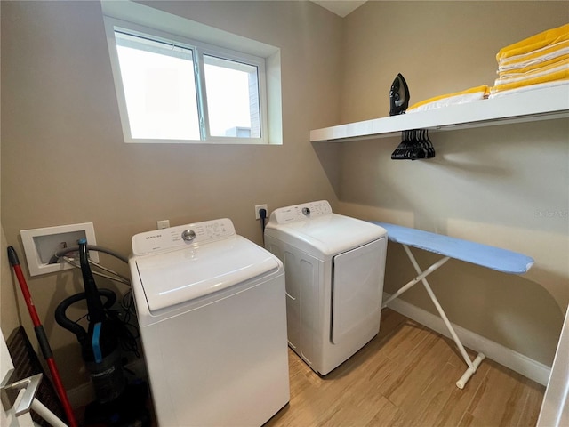 laundry area with baseboards, light wood-style floors, washing machine and dryer, and laundry area