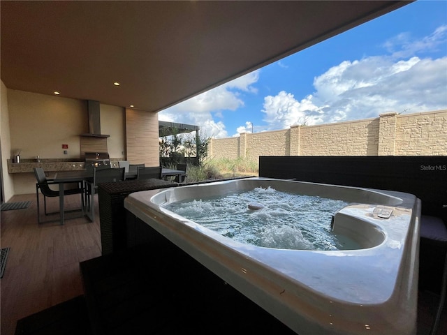 exterior space with fence, area for grilling, exterior kitchen, and a hot tub