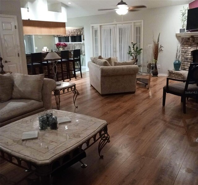 living room featuring wood-type flooring, ceiling fan, and a fireplace